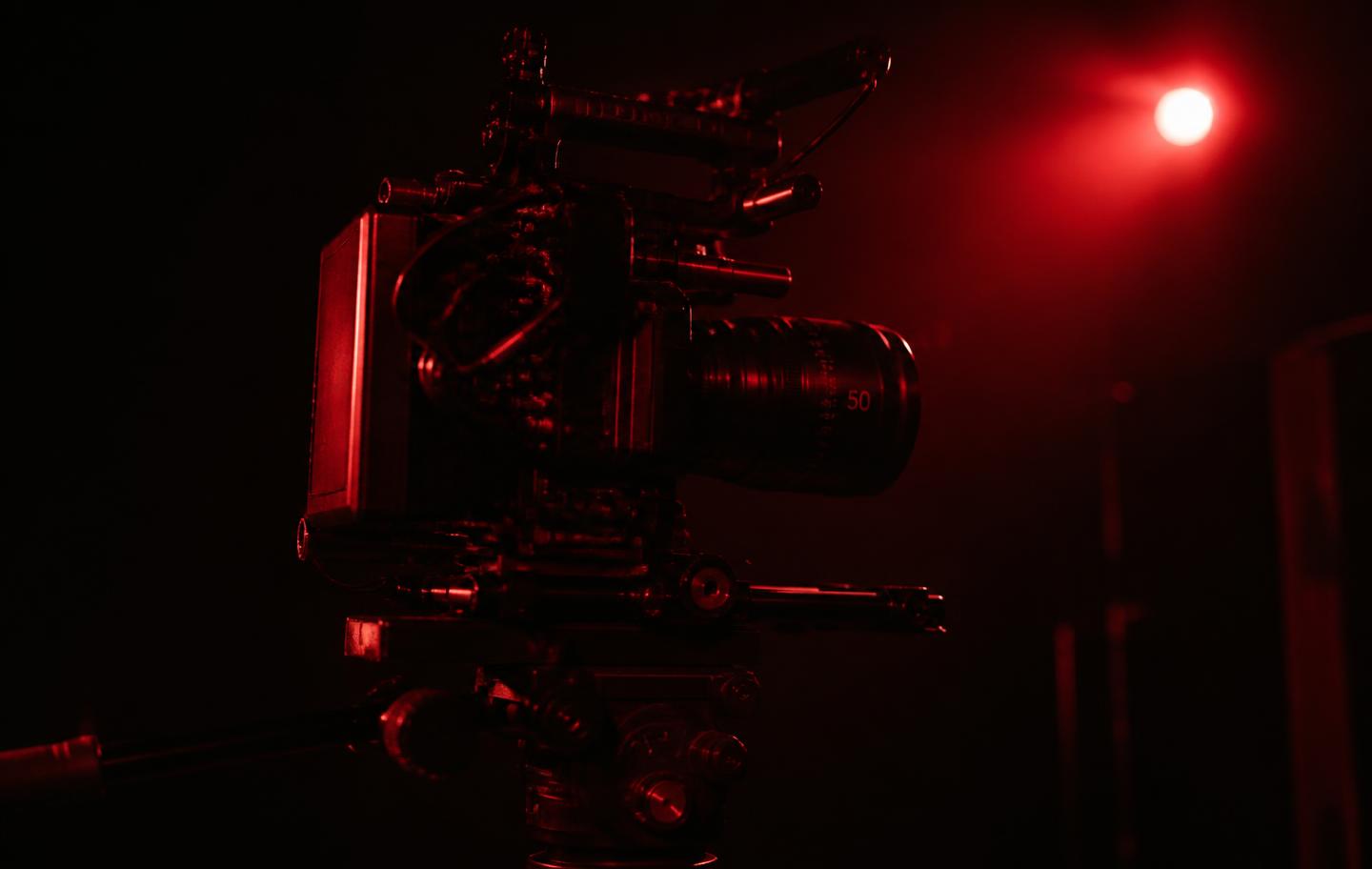 Professional cinema camera under dramatic red lighting